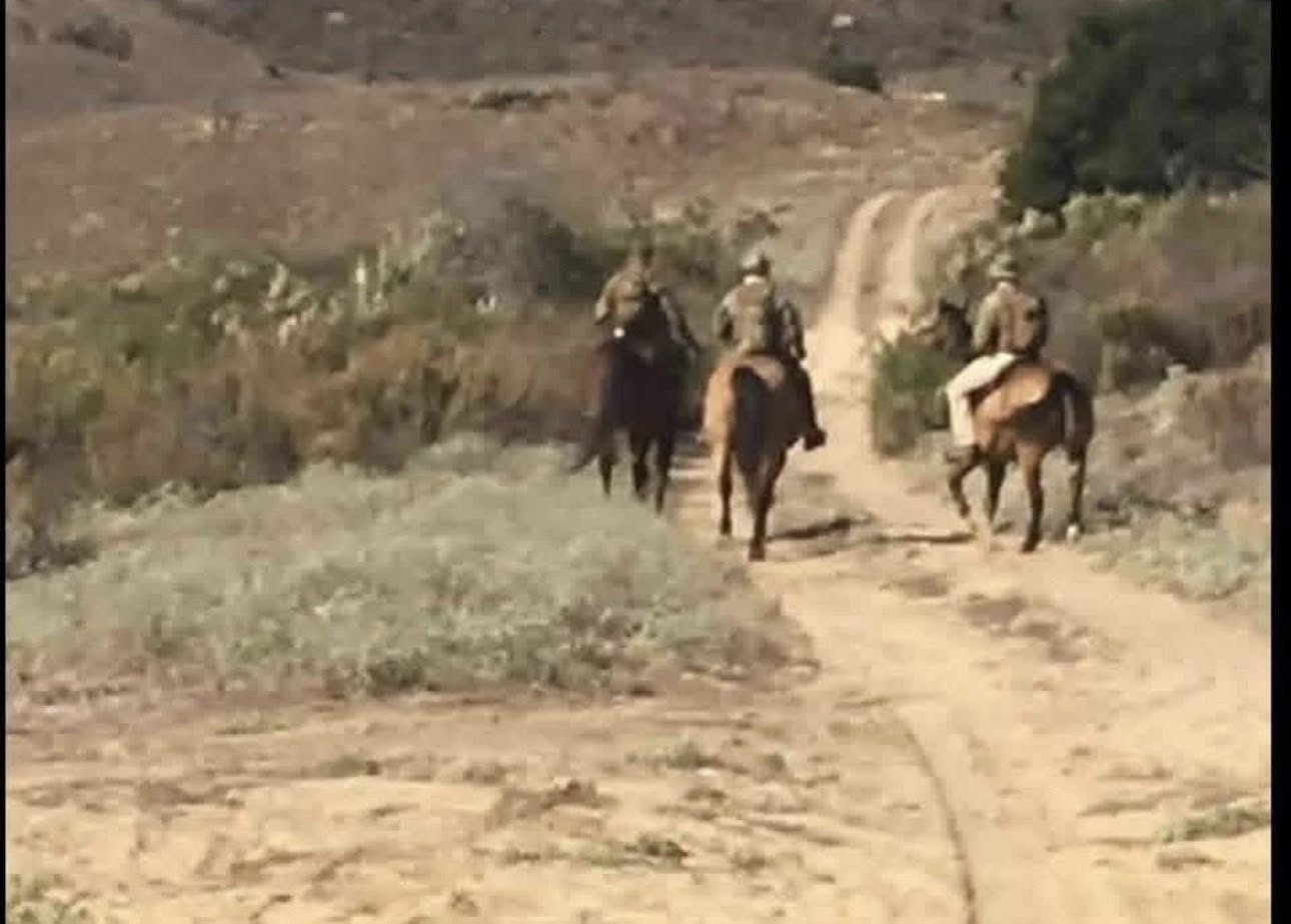 Three mounted trackers riding down a desert trail during a mantracking exercise
